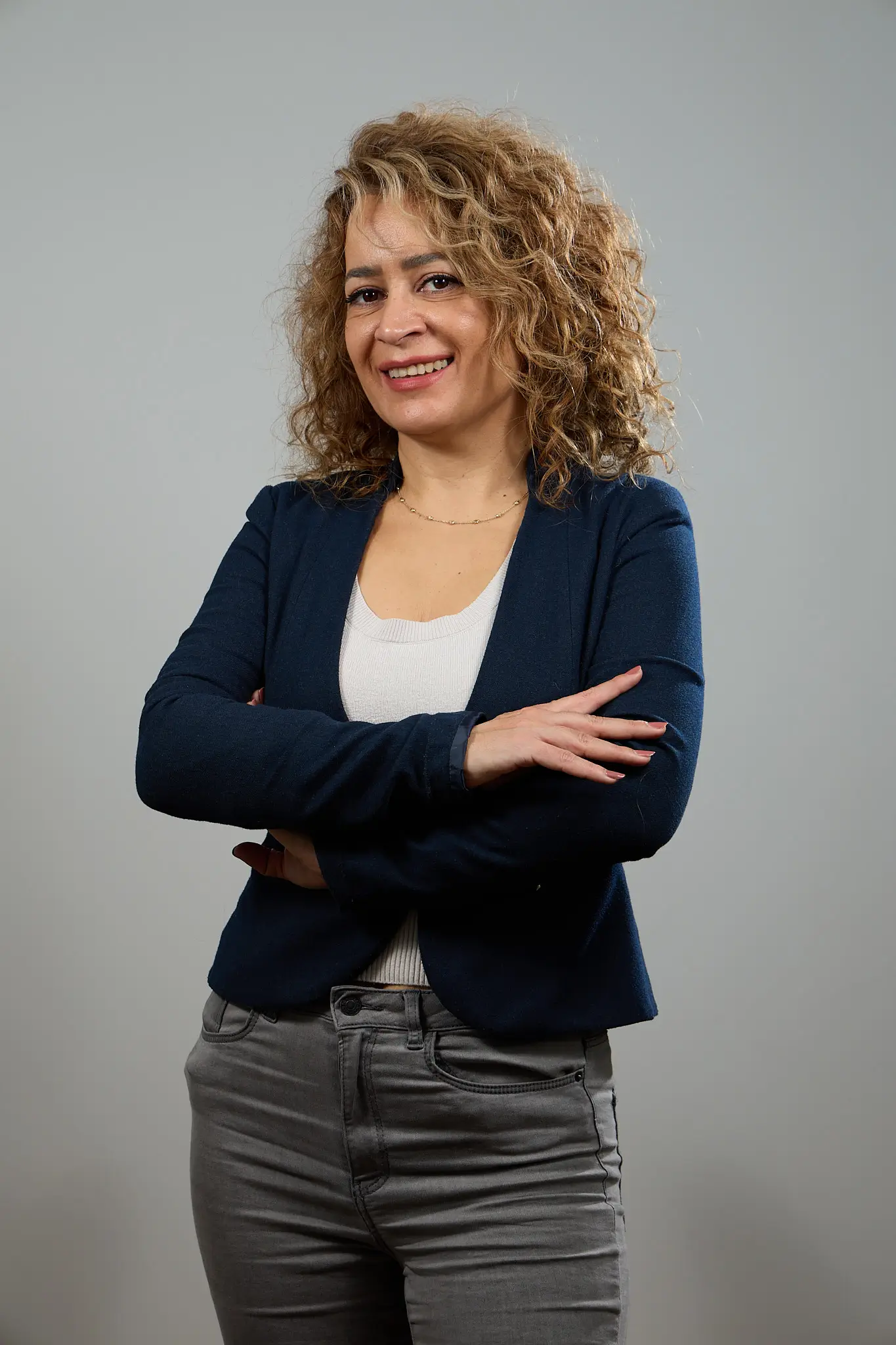 Portraitfotografie Bern – Person mit lockigem Haar, Arme verschränkt.